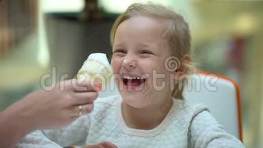 那个金发女孩有趣可爱的小女孩在大购物中心吃冰淇淋和喇叭。 一家人吃冰淇淋